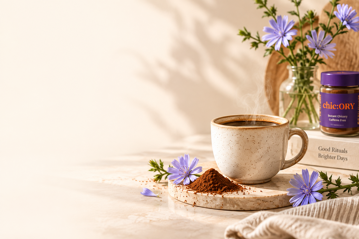 A ceramic cup of steaming coffee sits on a wooden tray with a small pile of brown powder, surrounded by purple flowers and a jar labeled chicORy, on a warm cream background.